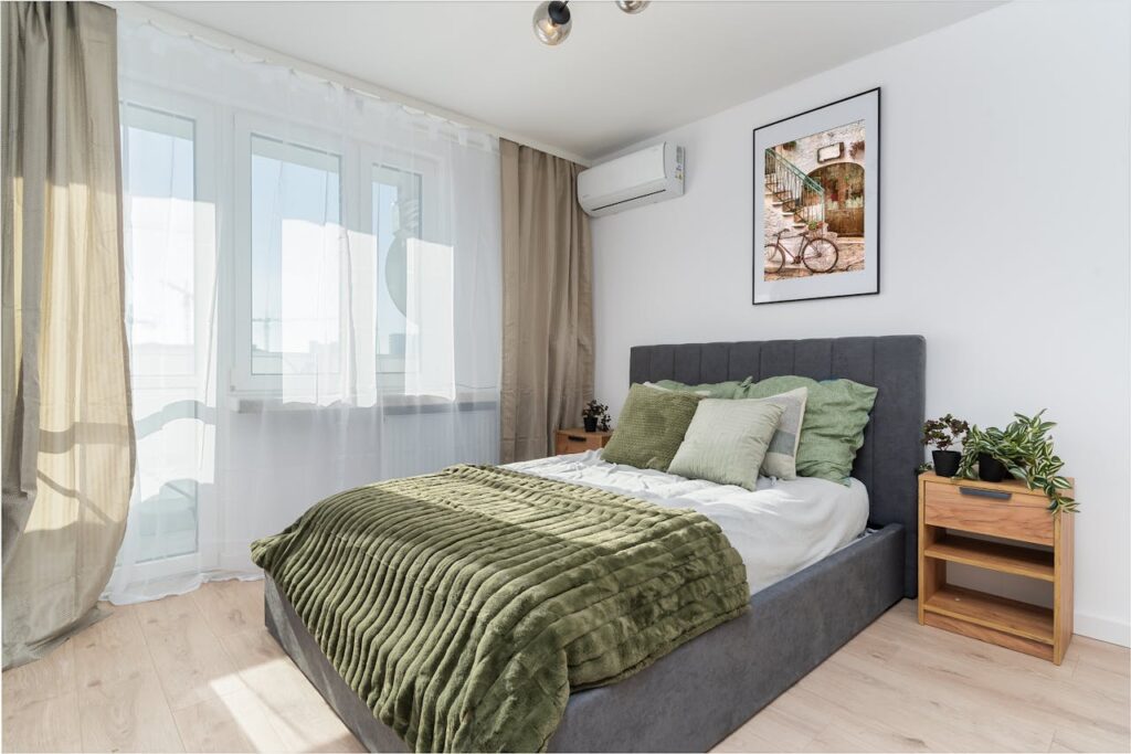 A stylish bedroom with green accents, natural light, and decorative plants.